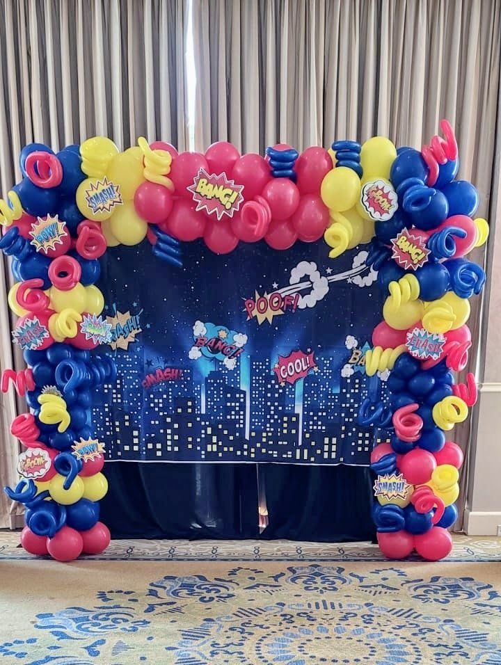 A room is decorated with balloons and a superhero theme.