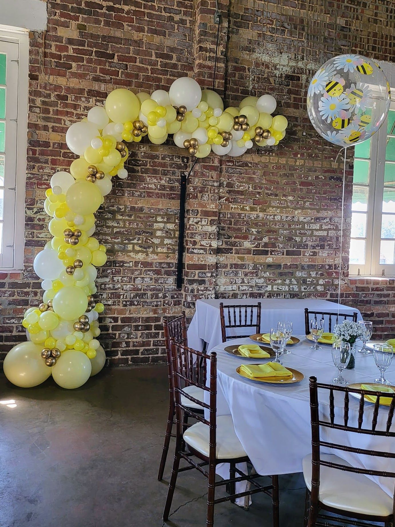 A room with a table and chairs decorated with yellow and white balloons.