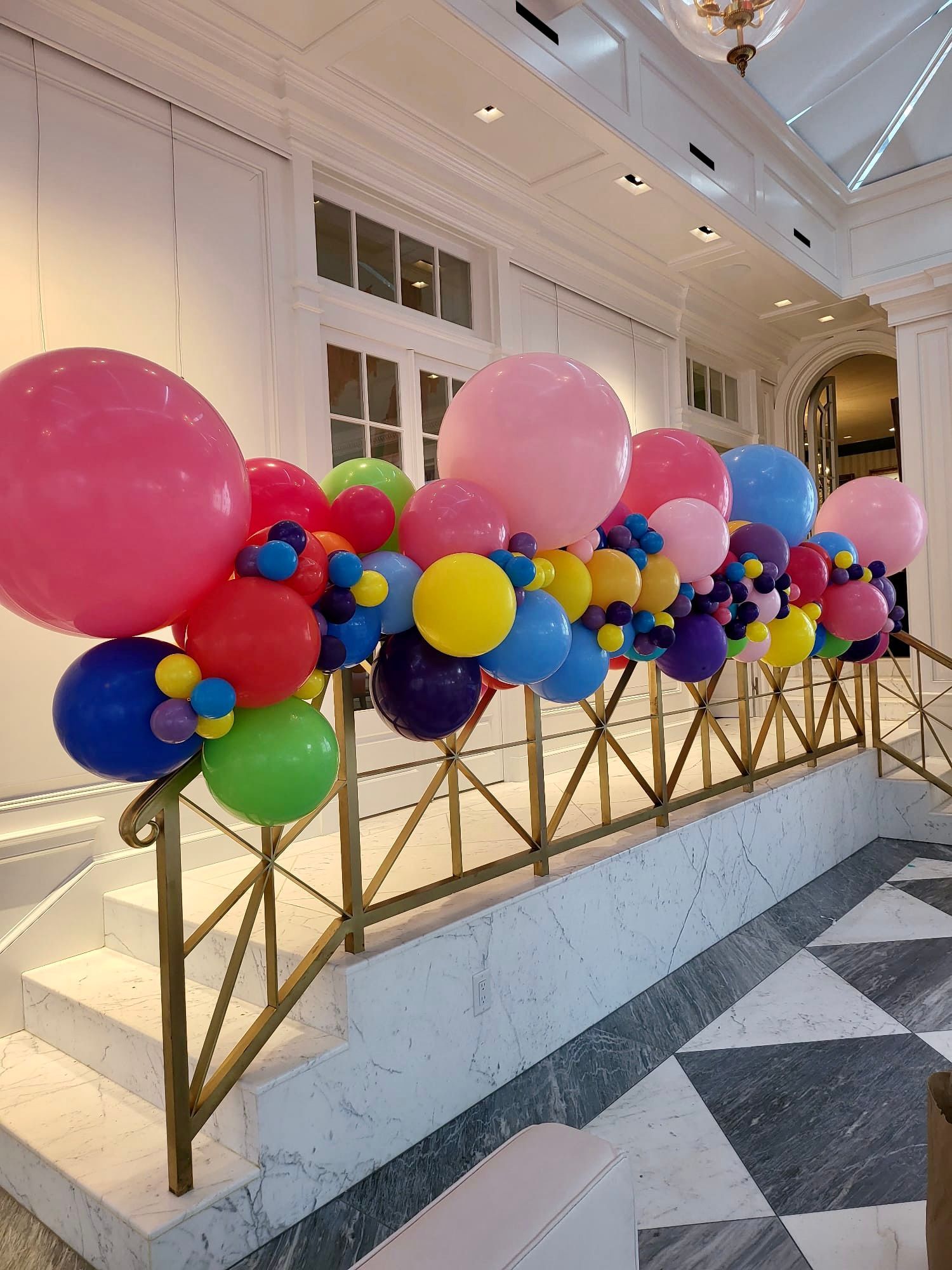 A bunch of colorful balloons are hanging from a railing in a room.