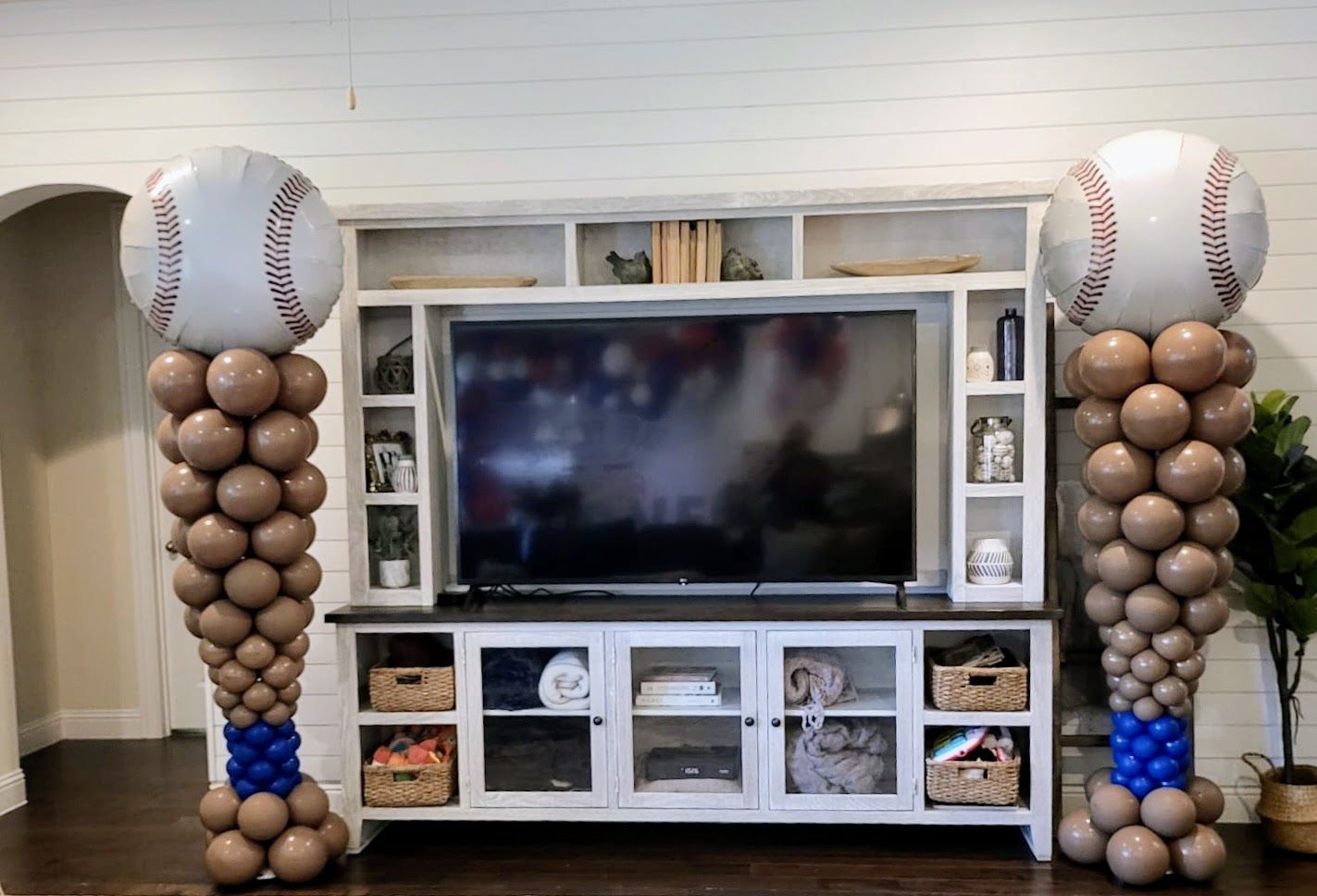 A living room with balloons in the shape of baseballs and a television.