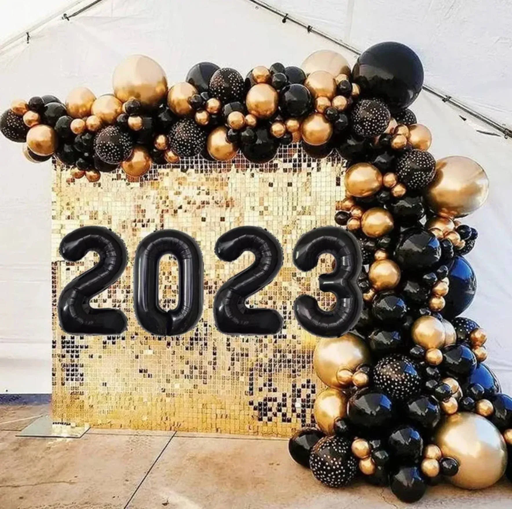 A wall decorated with black and gold balloons and the year 2023.
