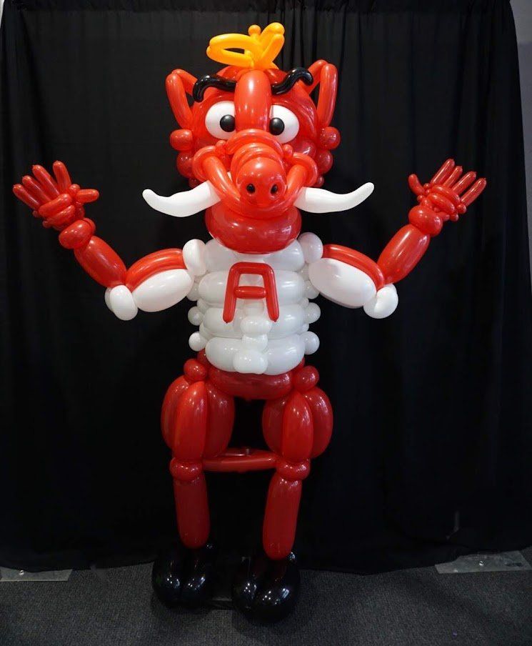 A dragon made out of red and white balloons with the letter a on his chest