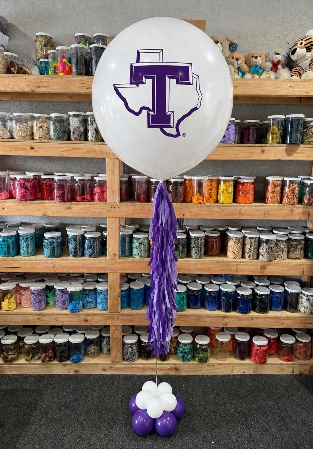 A jumbo helium balloon personalized with Tarleton State university logo and color, with matching colored tassels..