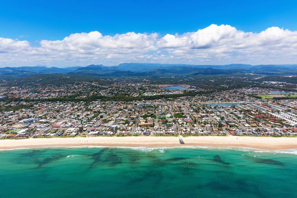 An Aerial View Of A Beach With A City In The Background — Salt Building & Pest Inspections in Elanora, QLD