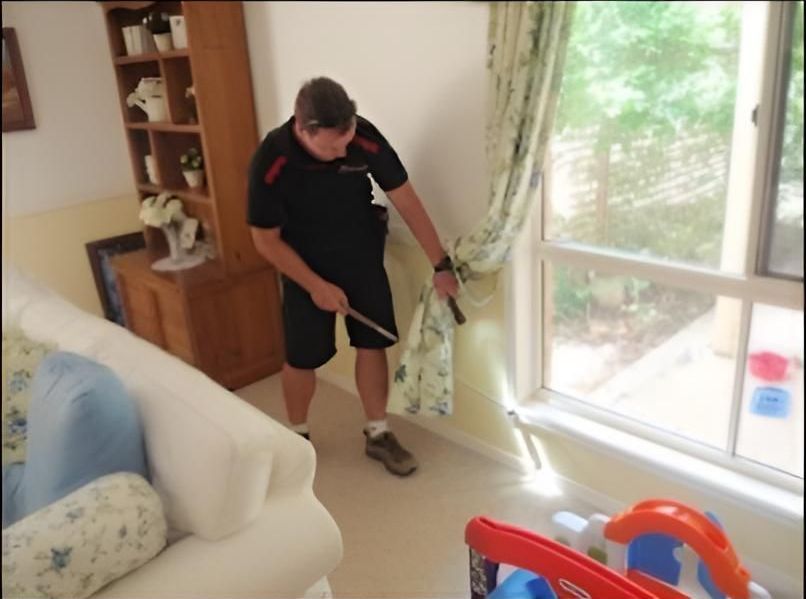 Man in Black Uniform Pointing at Curtains in a Living Room With a Window — Salt Building & Pest Inspections in Currumbin Valley, QLD