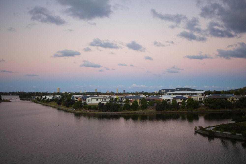 A Large Body Of Water Surrounded By Buildings And Trees At Sunset — Salt Building & Pest Inspections in Varsity Lakes, QLD