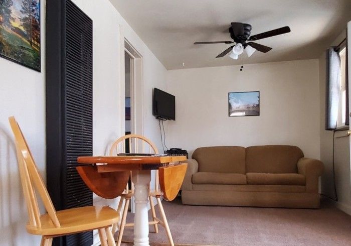 A bed with white pillows, a green and white striped blanket, and a chest of drawers in a room with a window.