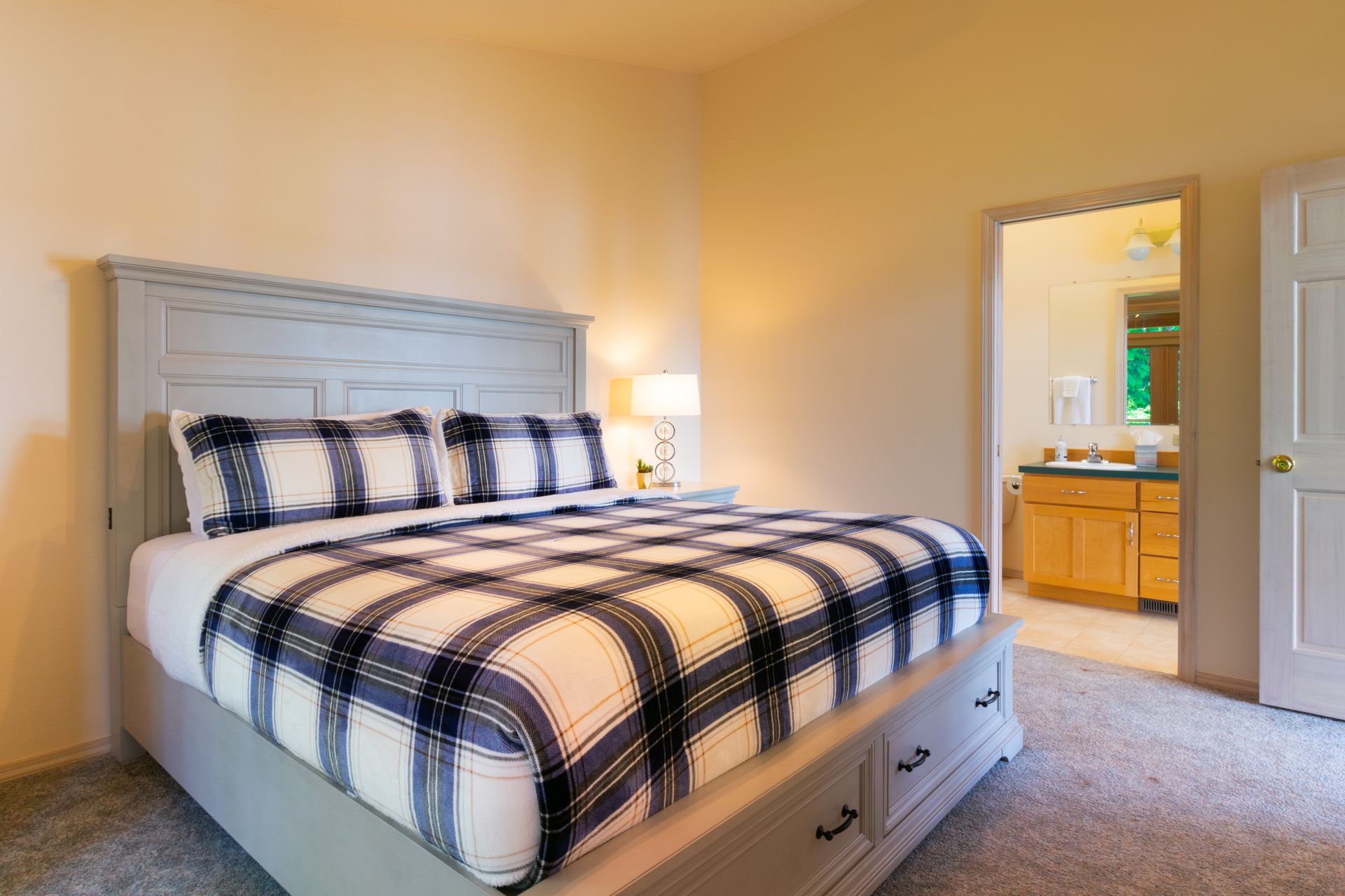 A bedroom with a large bed with a plaid comforter.