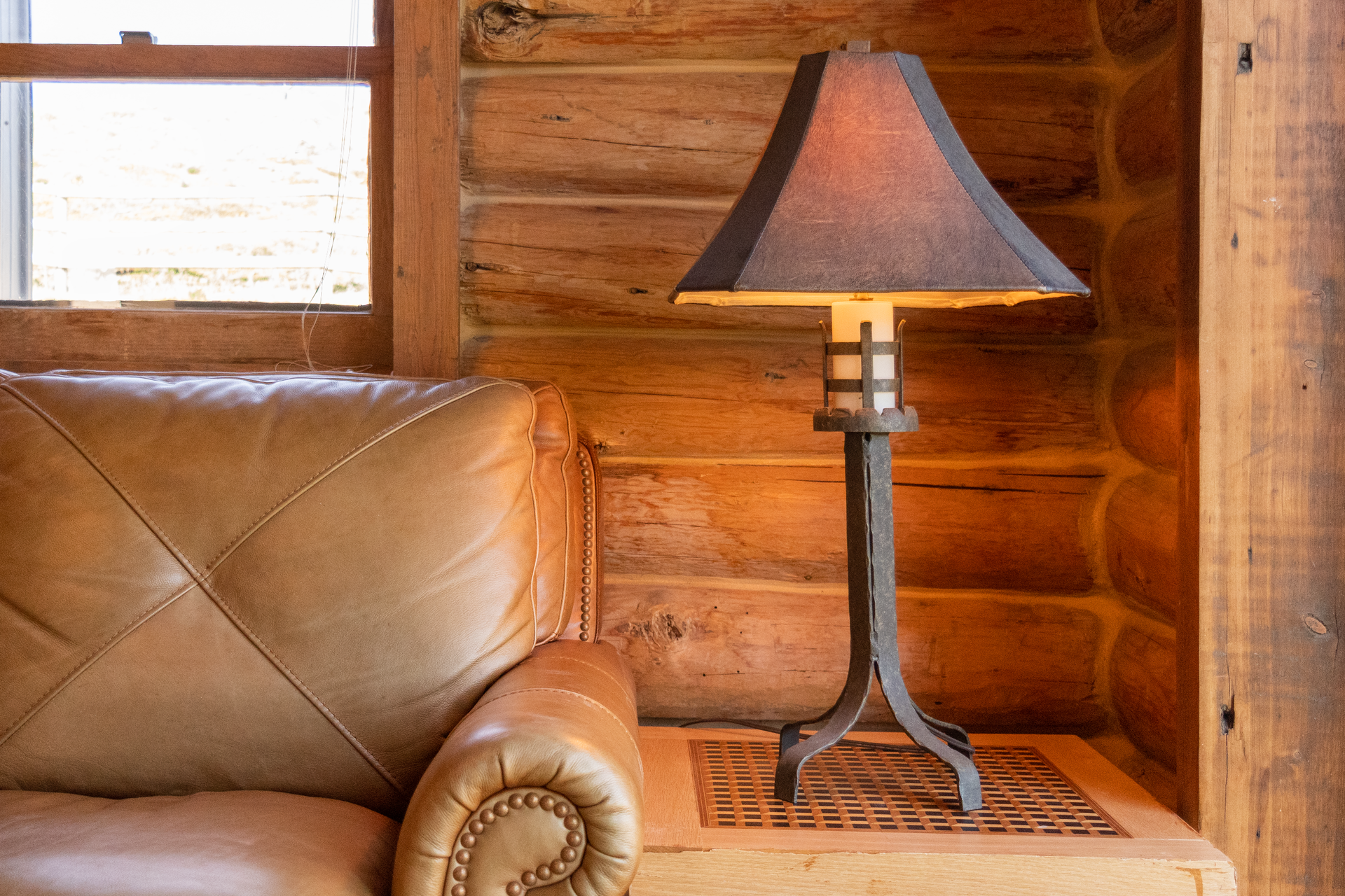 Table lamp with rust-colored shade and metal base on wooden table.