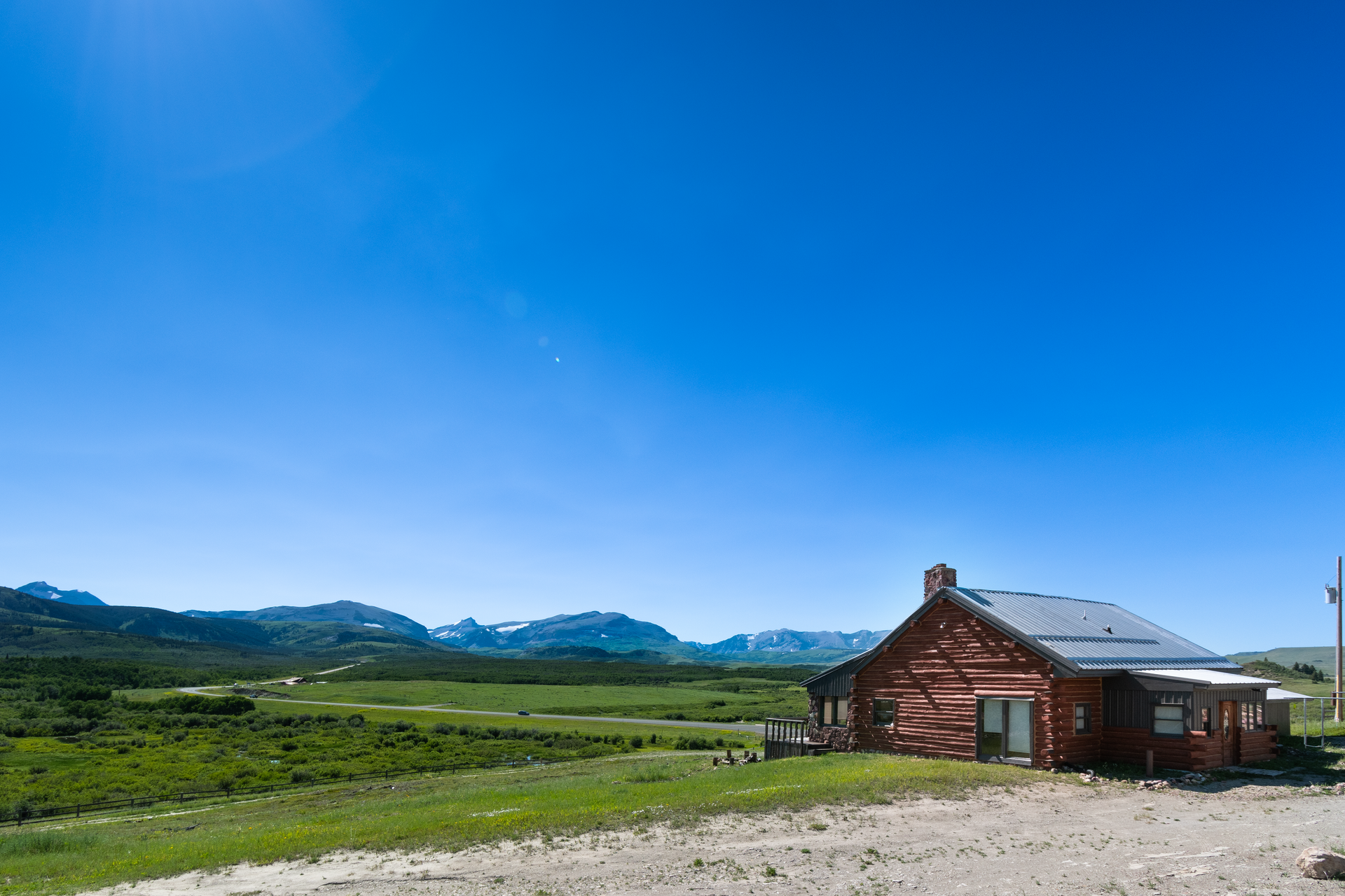 Wooden cabin with attached garage under a bright blue sky.