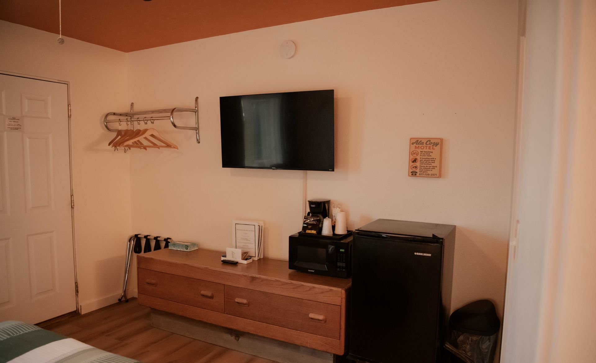 A motel room featuring a TV, dresser with a microwave and mini-fridge.