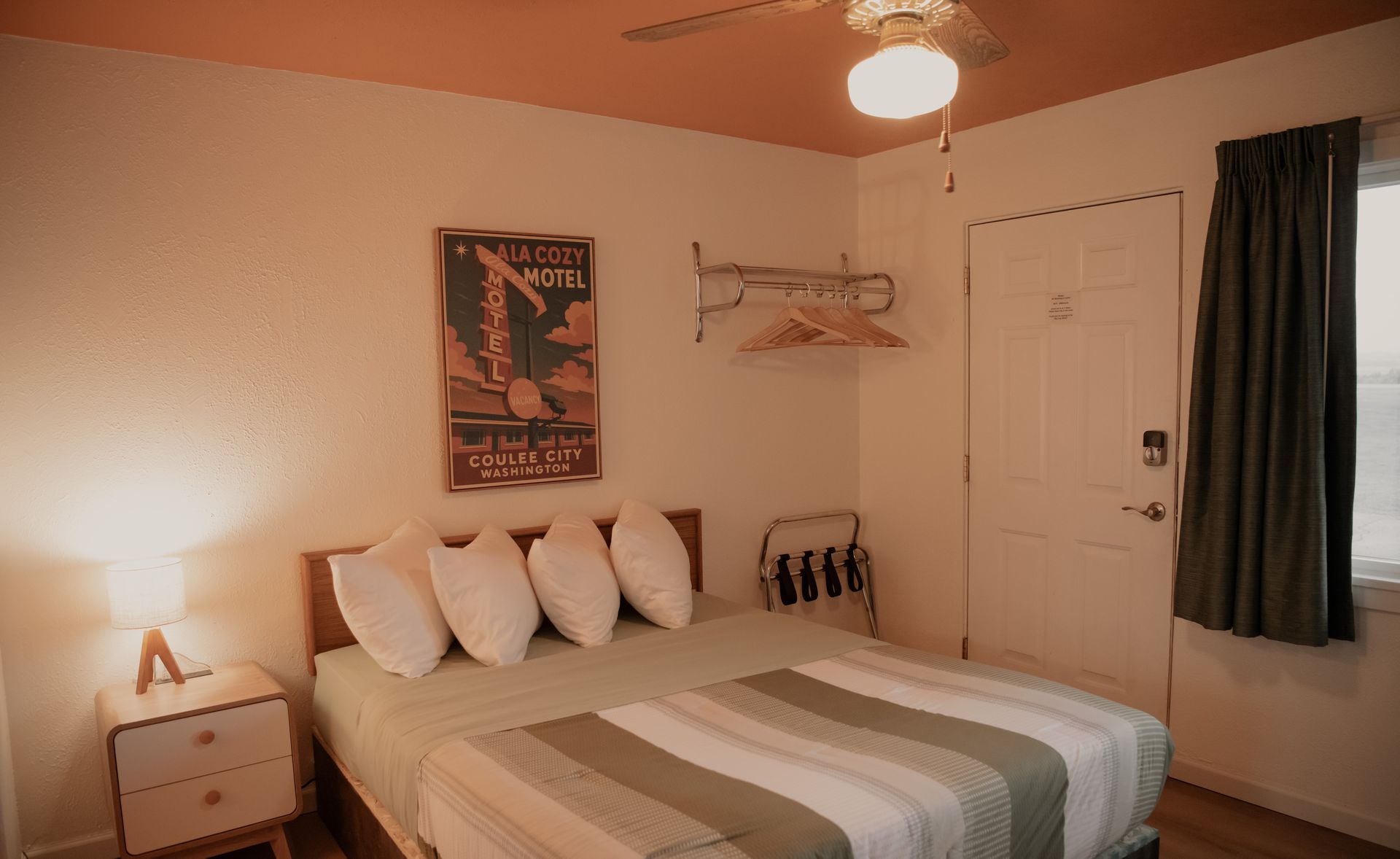 Bedroom with a bed, nightstand, door, and a poster on the wall. The ceiling is orange.