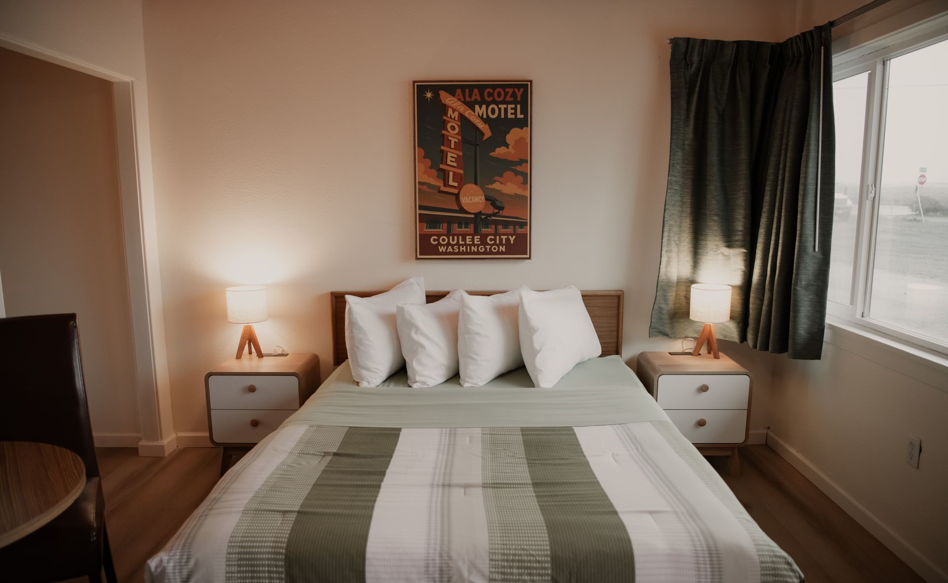 Bedroom with bed, nightstands, artwork, curtains, and window.