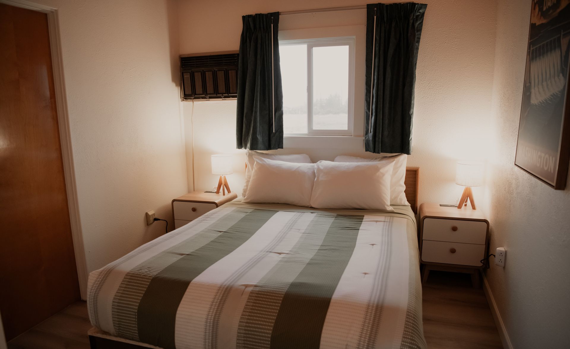 Bedroom with bed, nightstands, window, and curtains. Green and white striped bedspread.