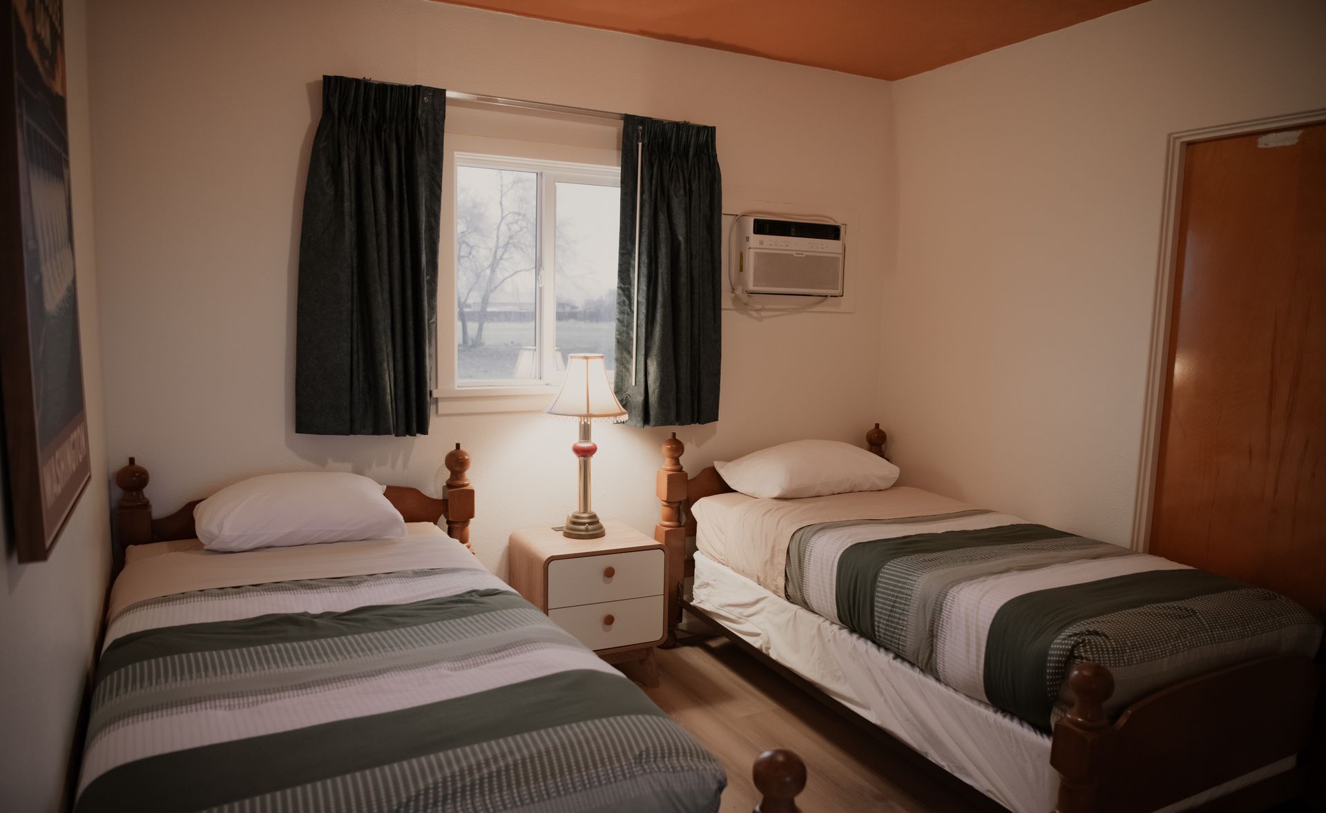 Two twin beds in a motel room. One bed has a green comforter, the other blue. 