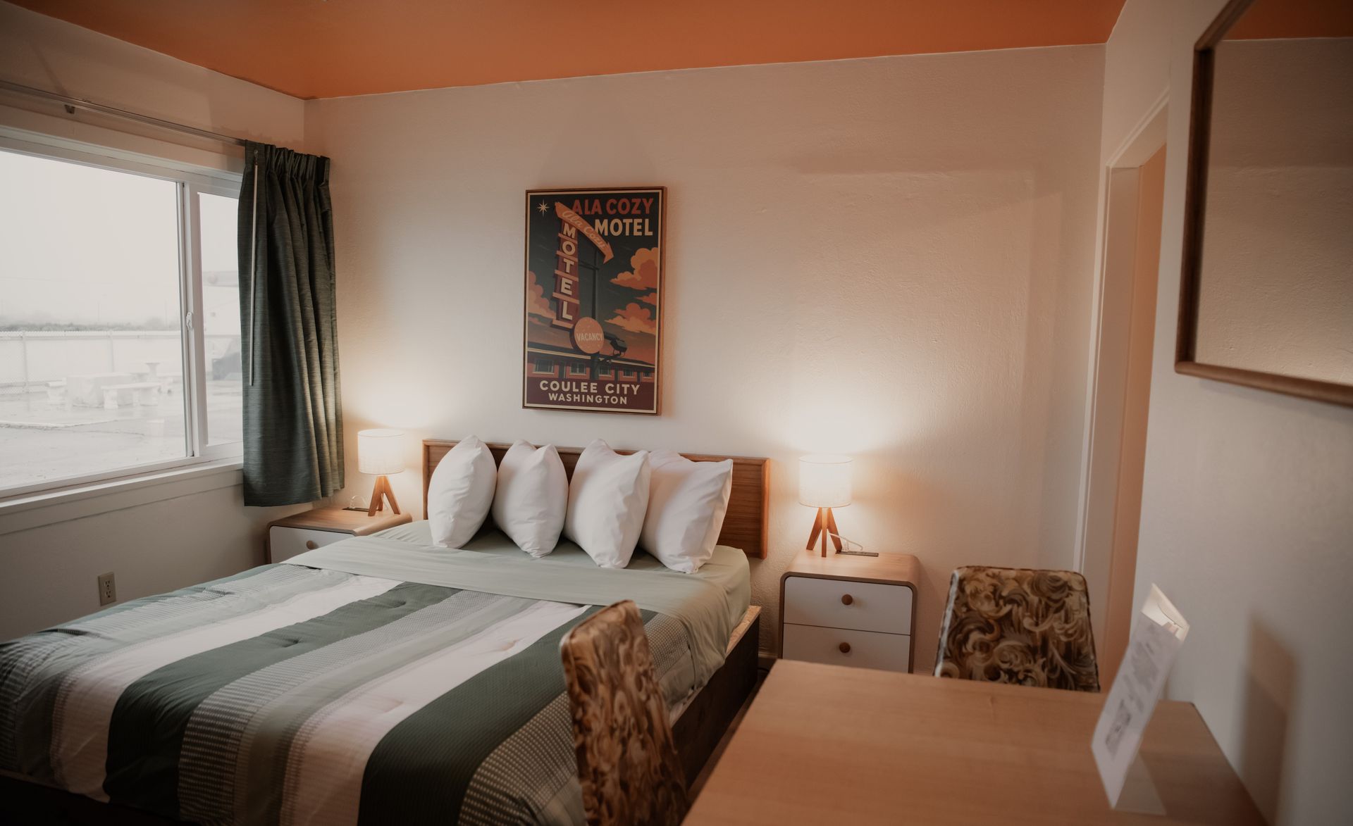 Bedroom with a bed, nightstands, poster, window, and desk. Green and white bedding, orange ceiling.