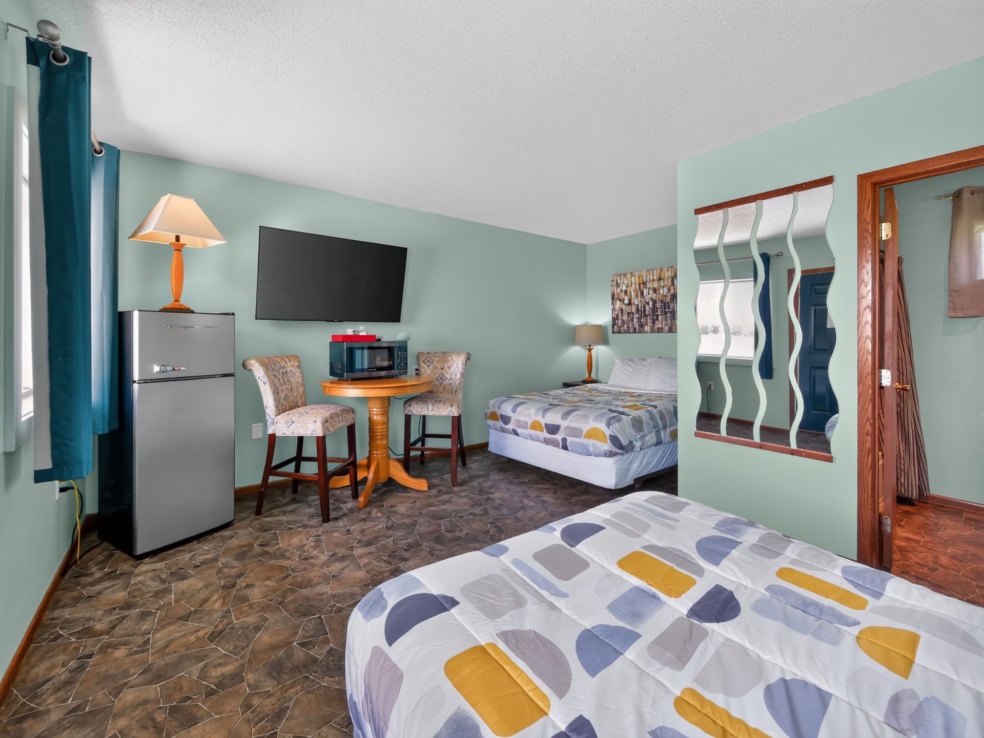 Cozy bedroom scene with a lit bedside lamp on a nightstand next to a bed with white linens and pillows.