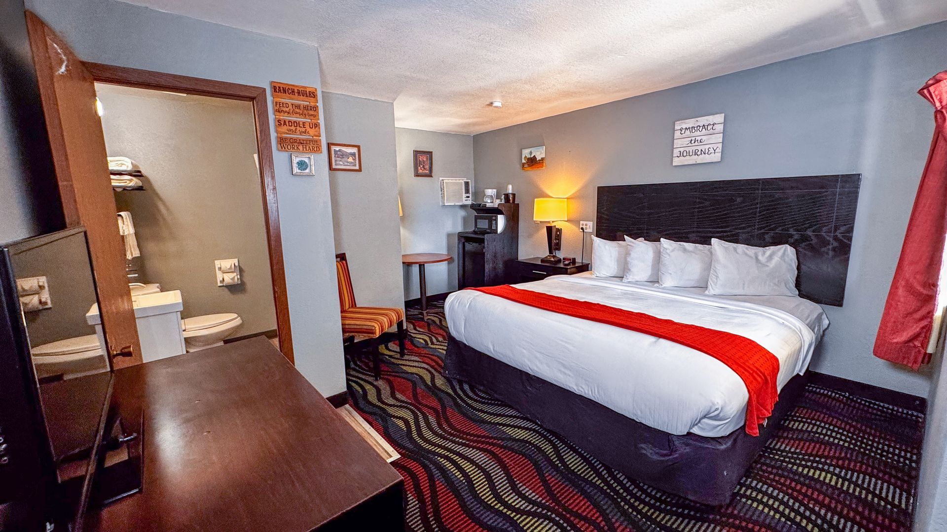 Hotel room with bed, red accents, and bathroom visible.