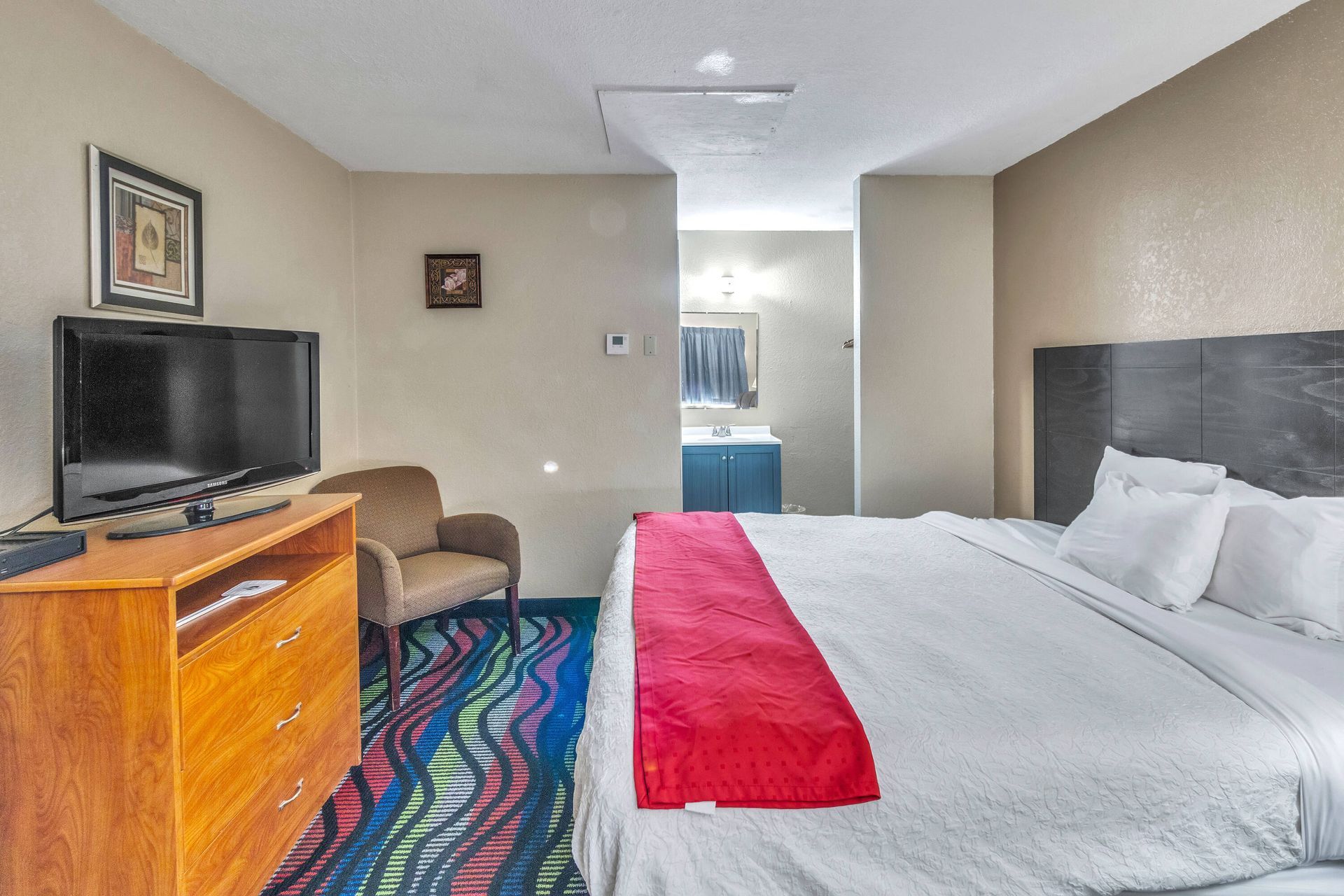 A hotel room with two double beds, featuring green and white striped bedding, set against pink walls and a ceiling fan.
