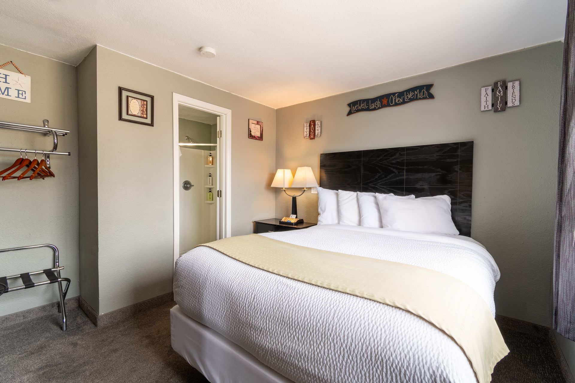 A hotel room with two double beds, featuring green and white striped bedding, set against pink walls and a ceiling fan.