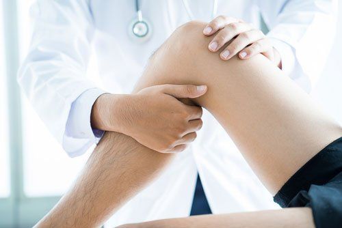 medico tocca il ginocchio di un paziente