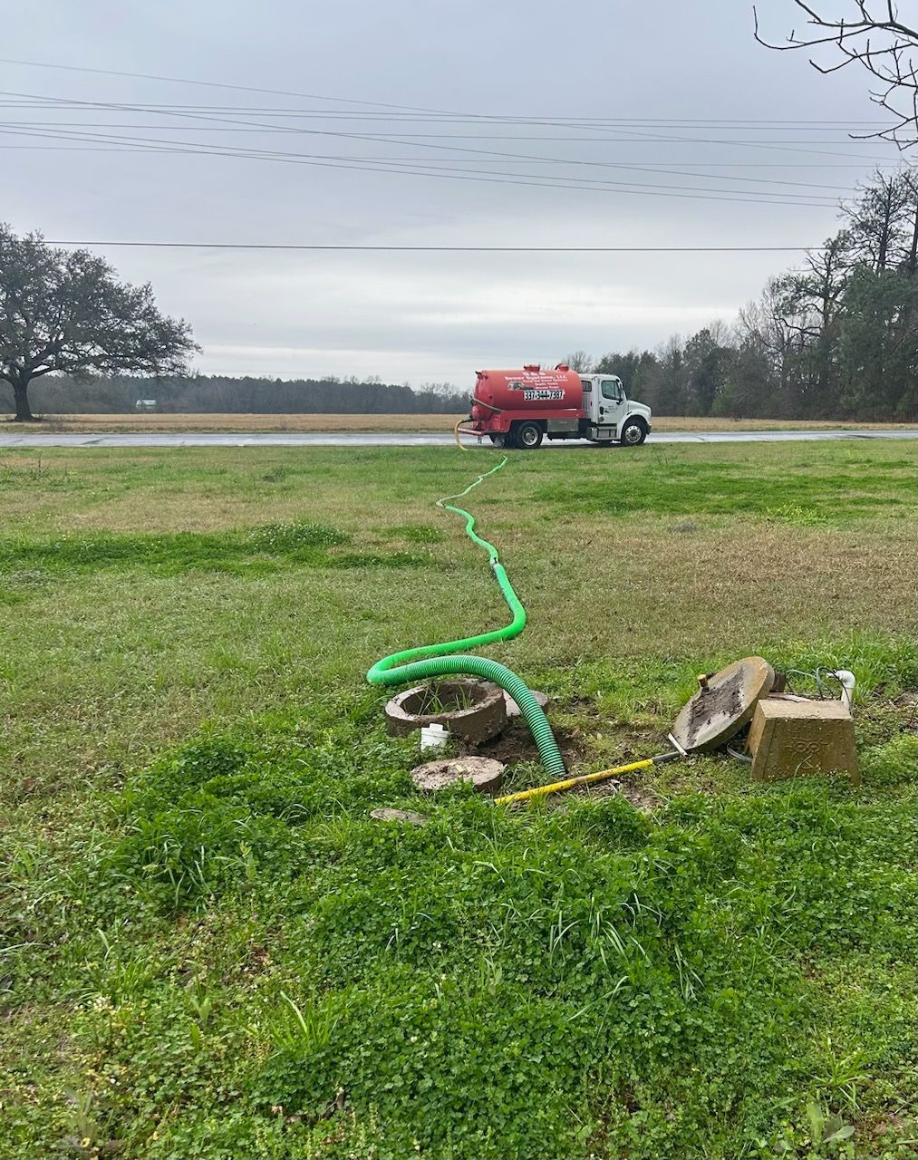 A septic tank is being pumped into a field with a truck in the background.