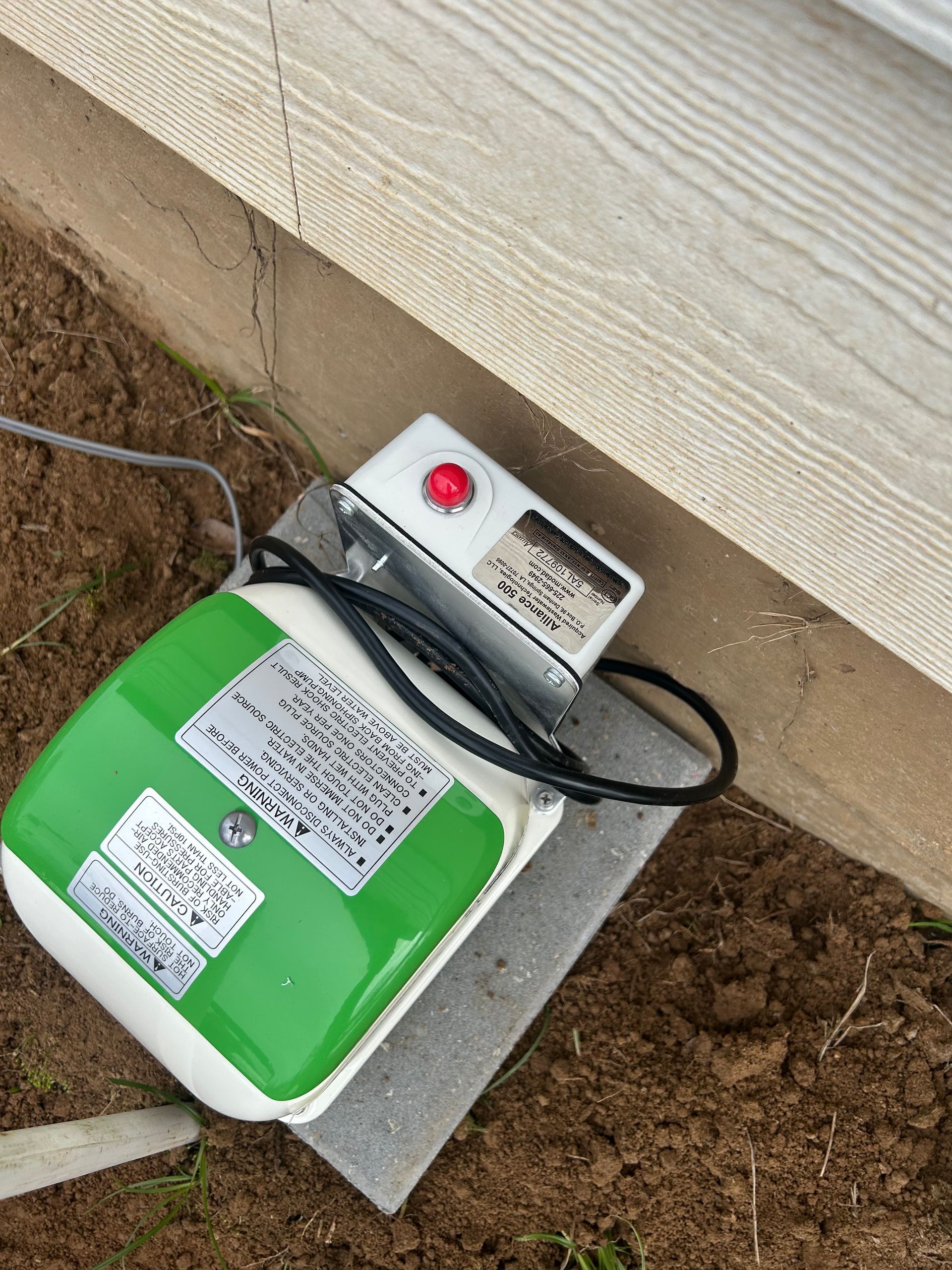 A green and white device is sitting on the ground next to a wall.