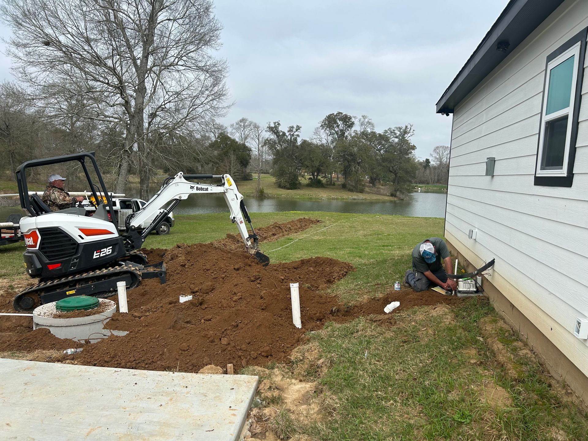 A man is digging a hole in the ground next to a house.