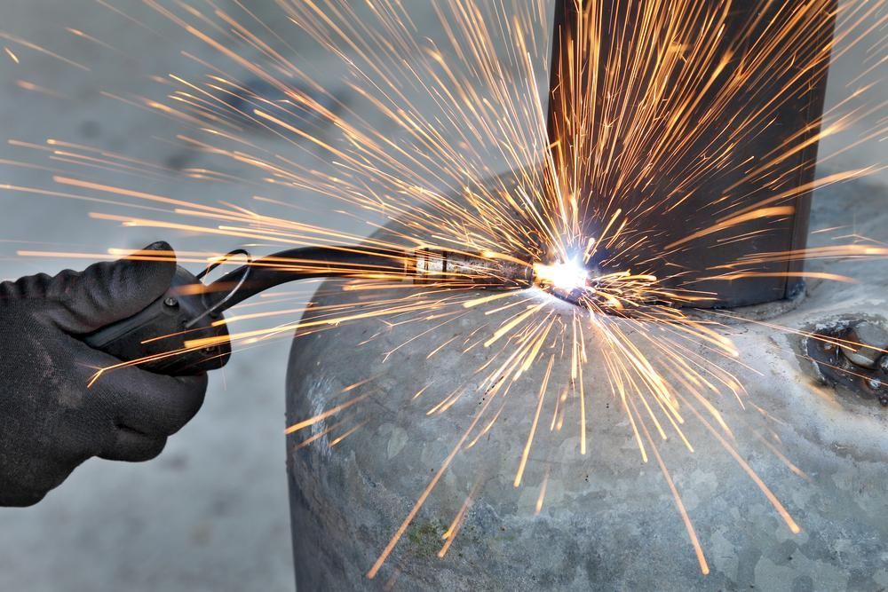 A Person is Welding a Piece of Metal With Sparks Coming Out of It — Kymar Steel Fabrications in Central Coast, NSW