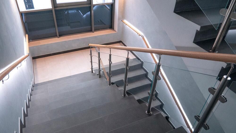 A Staircase With a Glass Railing and a Wooden Handrail — Kymar Steel Fabrications in Teralba, NSW