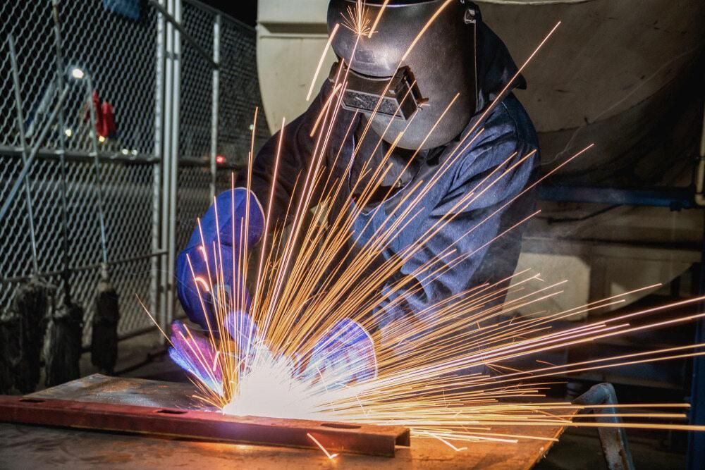 A Man is Welding a Piece of Metal in a Factory — Kymar Steel Fabrications in Lake Macquarie, NSW