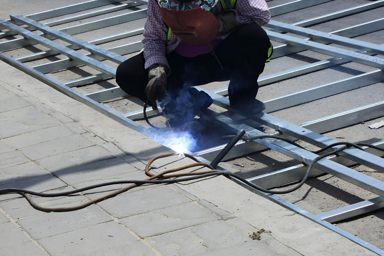 A Man is Welding a Metal Structure on the Ground — Kymar Steel Fabrications in Teralba, NSW