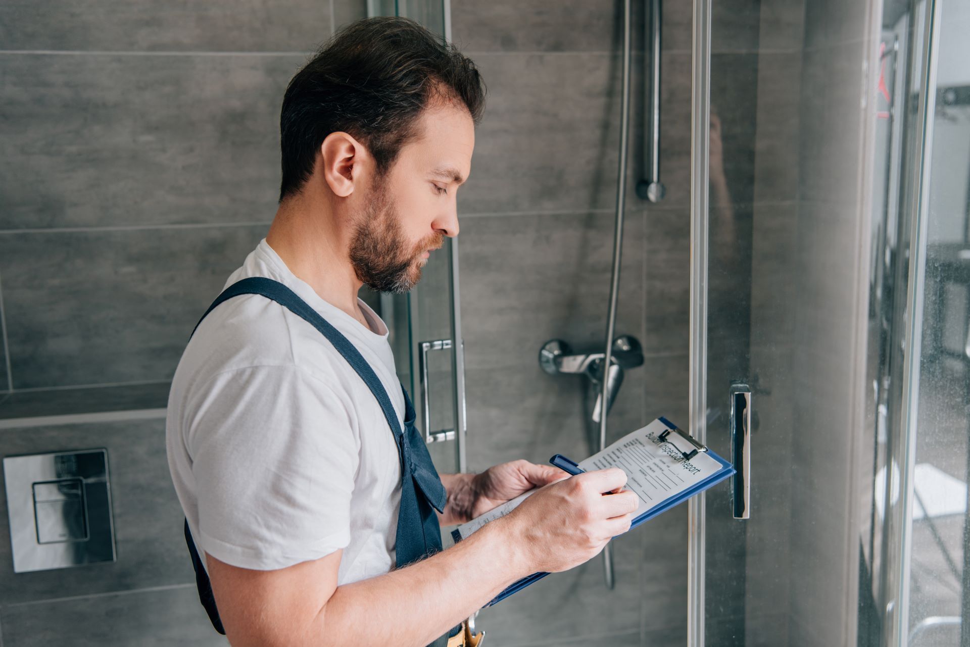a man is standing in a bathroom looking at a clipboard .