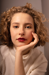 A Woman with Curly Hair Is Wearing a White Sweater and Red Lipstick — Rejuved in Bateau Bay, NSW