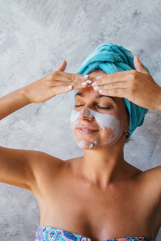 A Woman with A Towel Wrapped Around Her Head Is Applying a Mask to Her Face — Rejuved in Bateau Bay, NSW