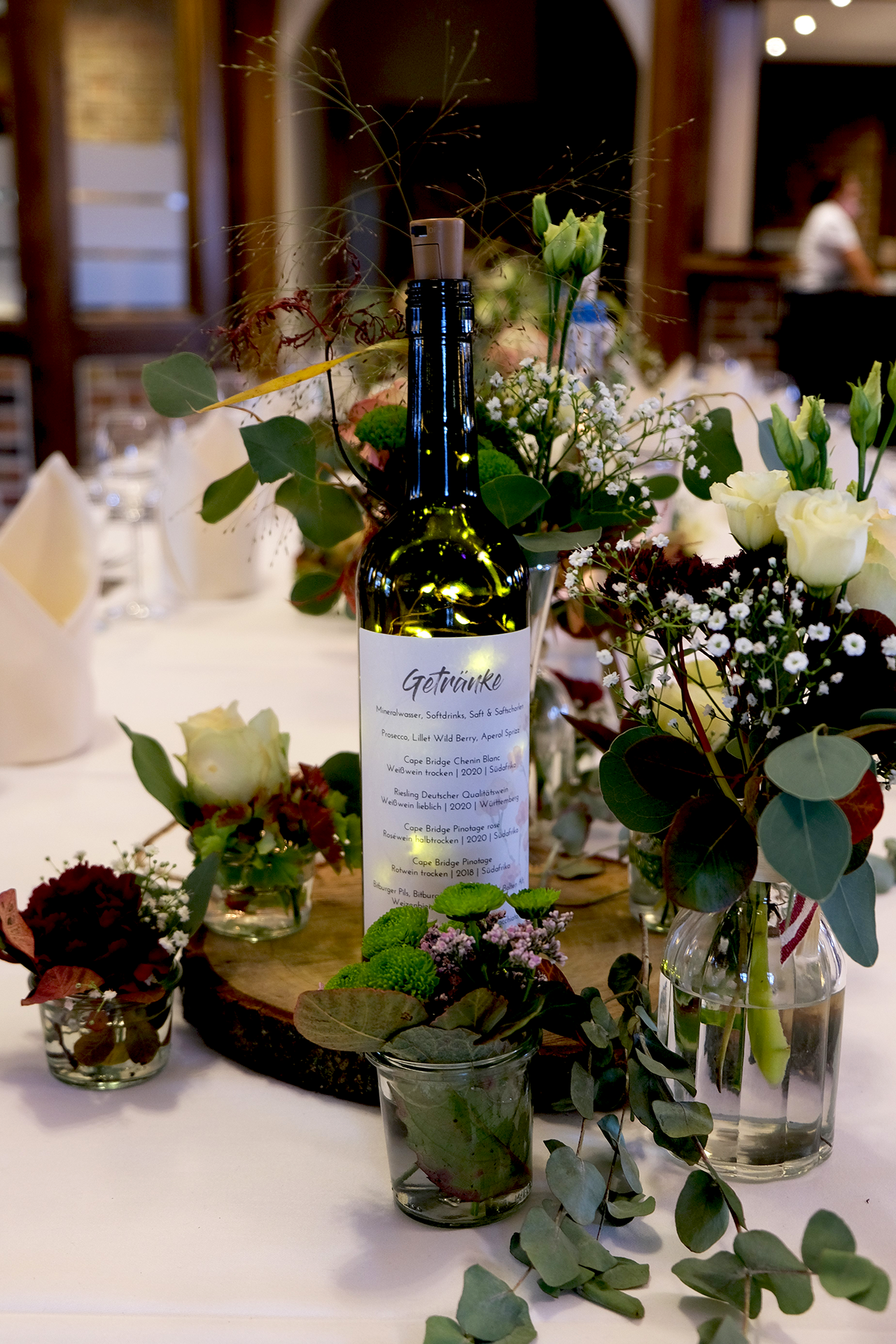 Getränkekarte Hochzeit, illuminierte Weinflasche mit Etikett auf dekoriertem Tisch