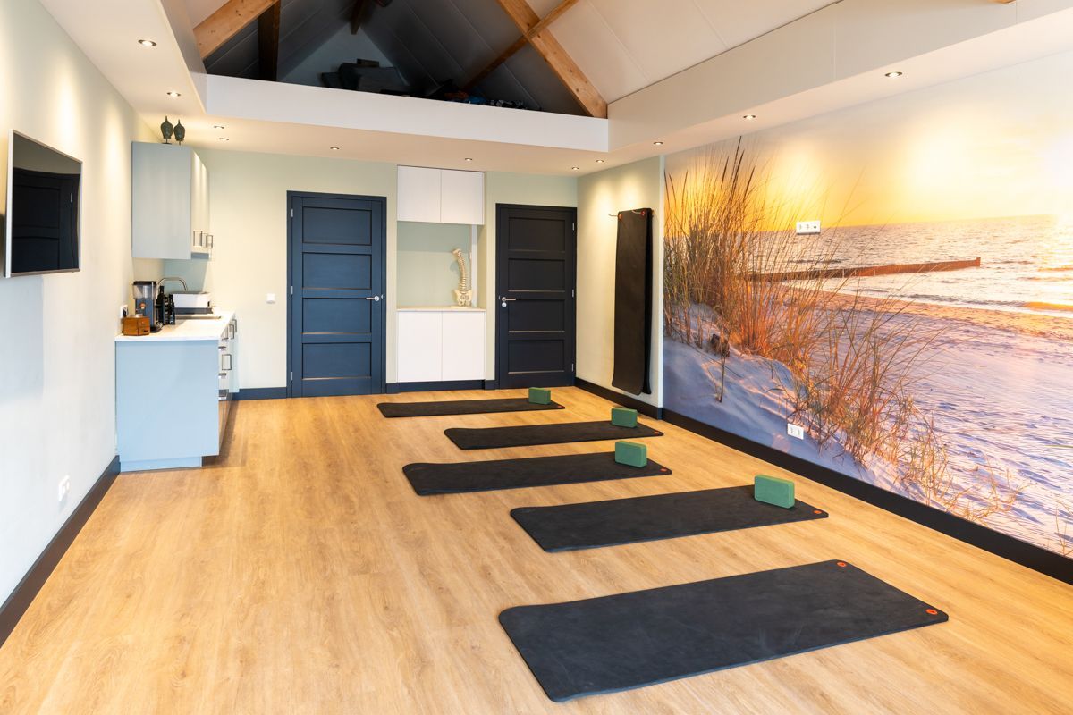 Yogastudio met matten, blokken, houten vloeren en een strandmuurschildering.