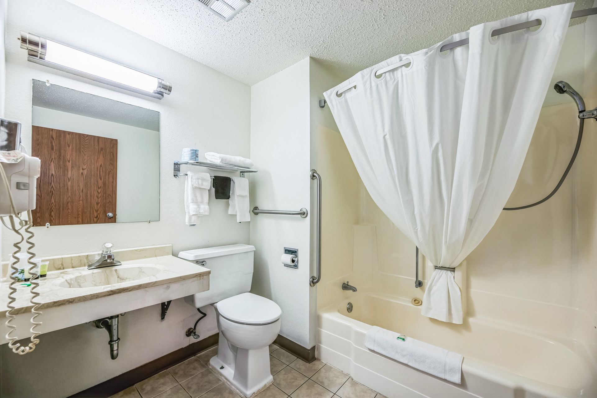 Bathroom with a tub/shower, toilet, sink, mirror, and white shower curtain.