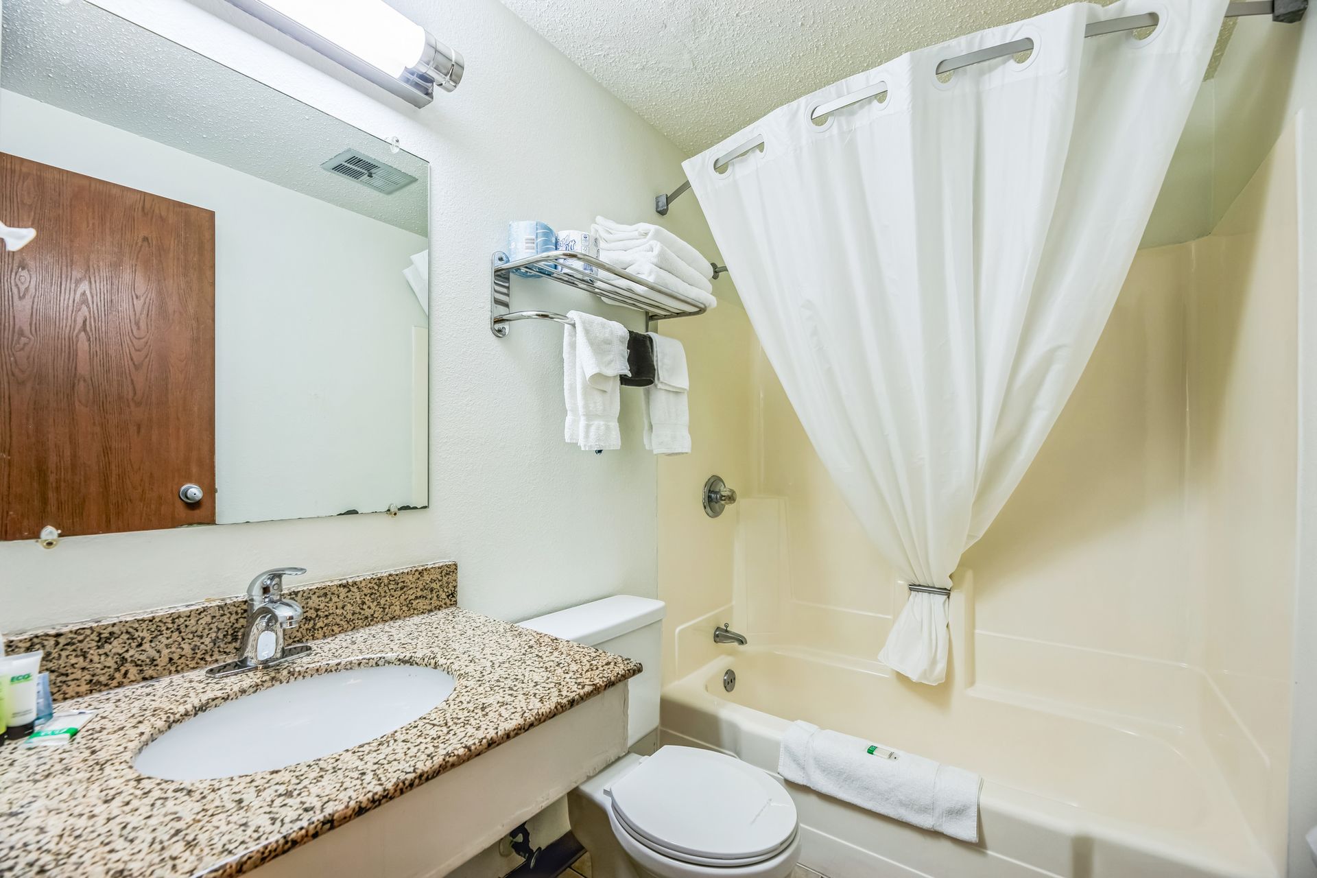 Bathroom with a sink, toilet, and bathtub with a shower curtain.