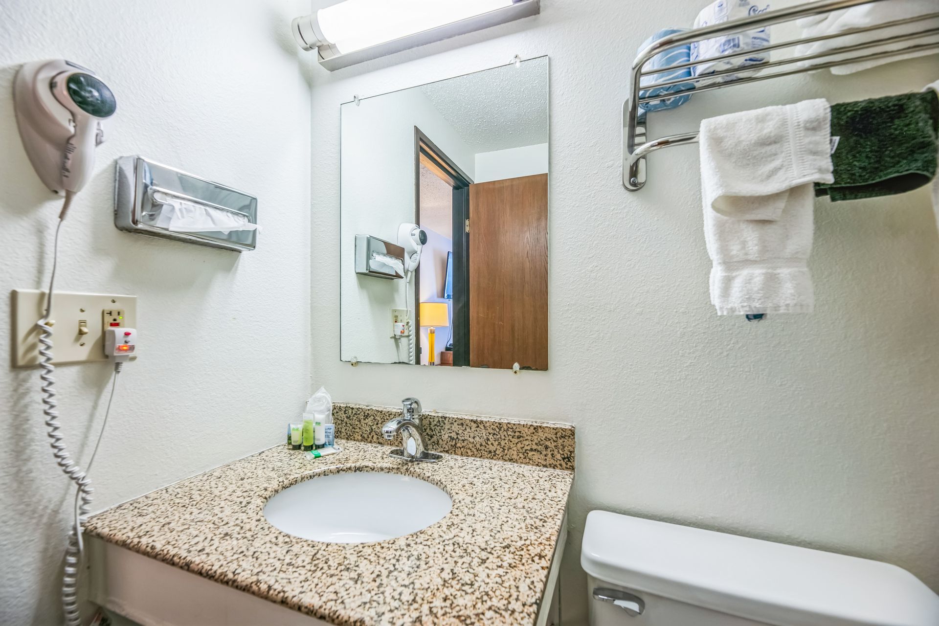 Bathroom with a sink, mirror, toilet, and towel rack.