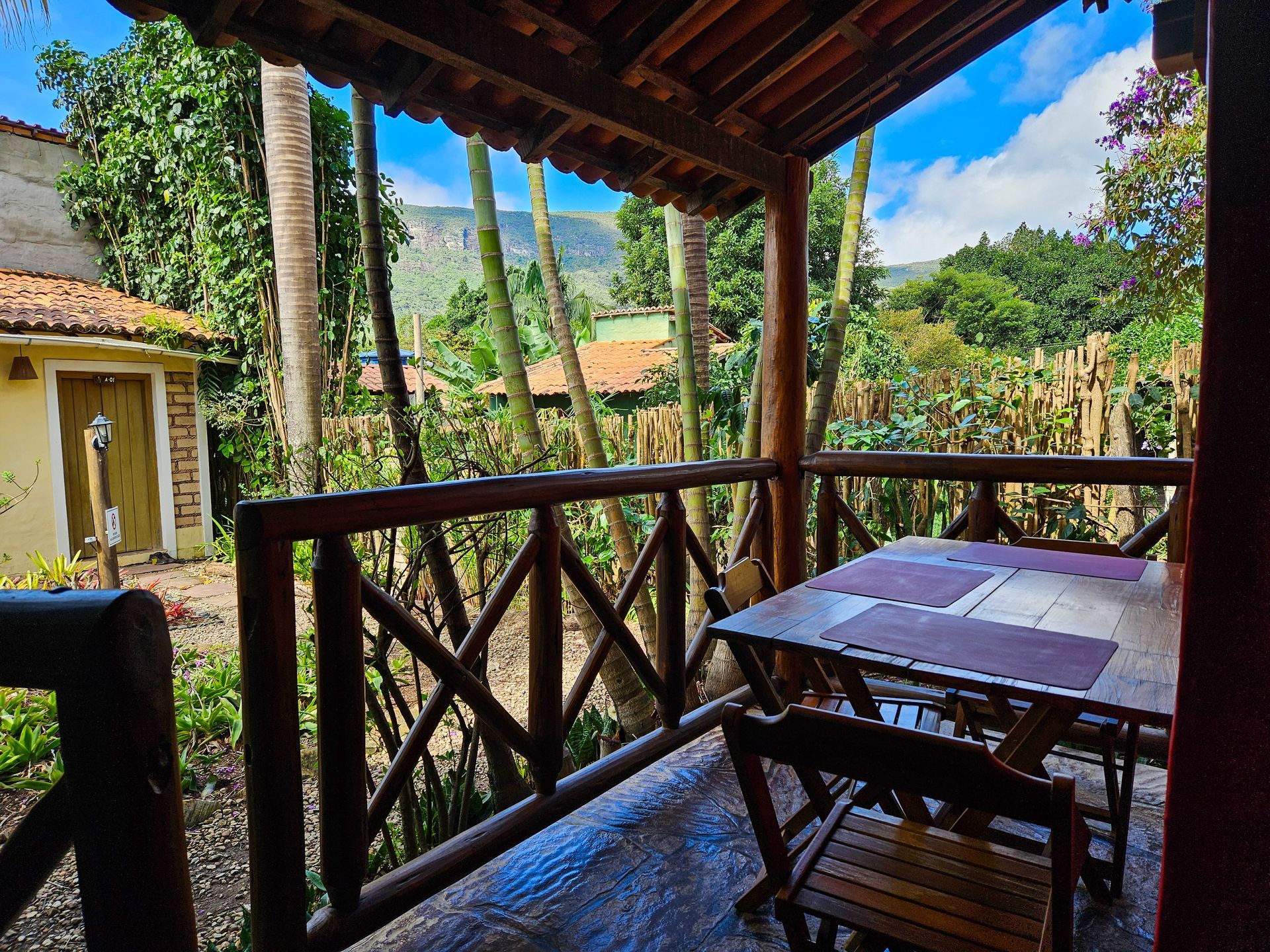 Uma varanda com mesa e cadeiras com vista para uma floresta