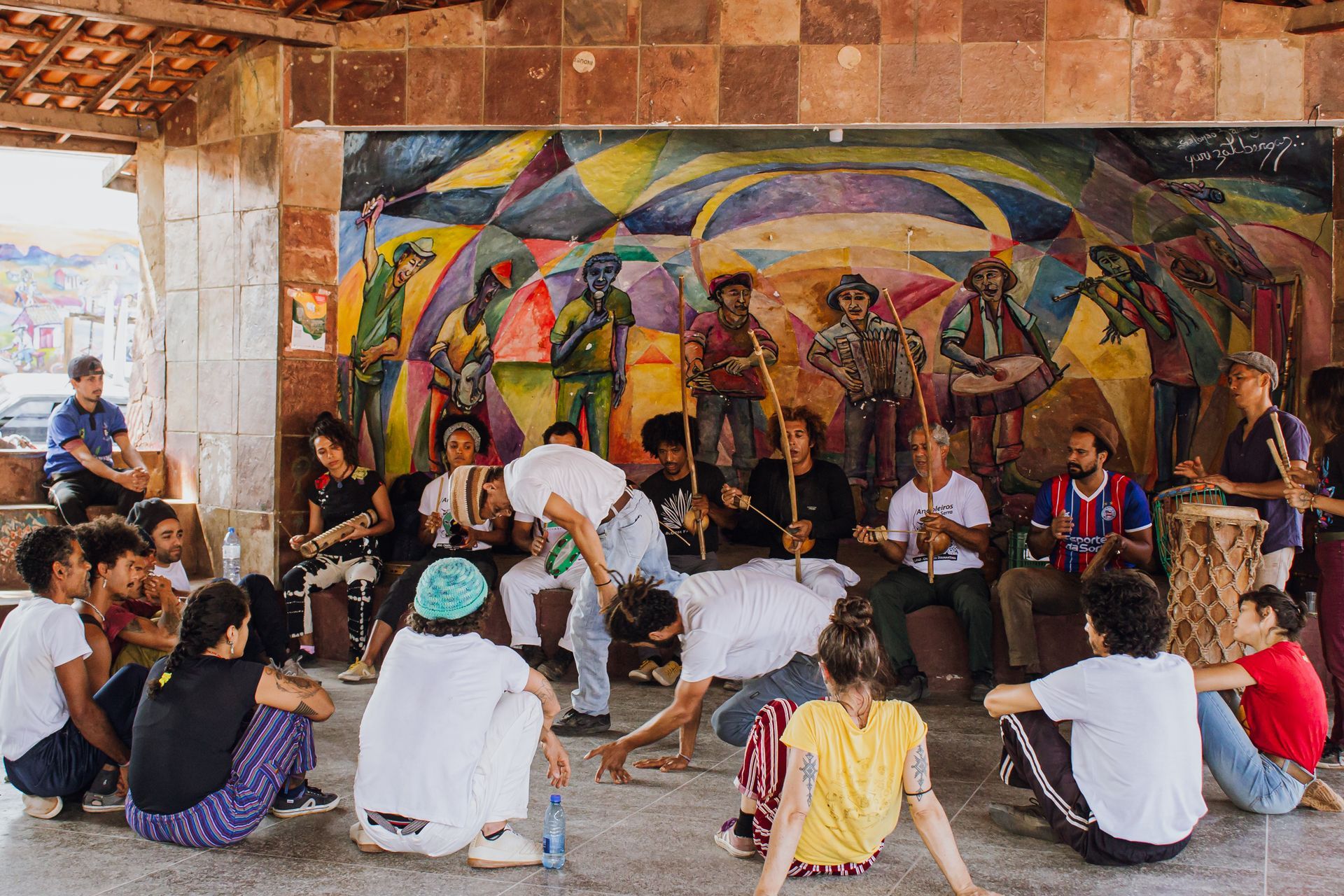 Um grupo de pessoas está sentado em círculo em frente a um mural.
