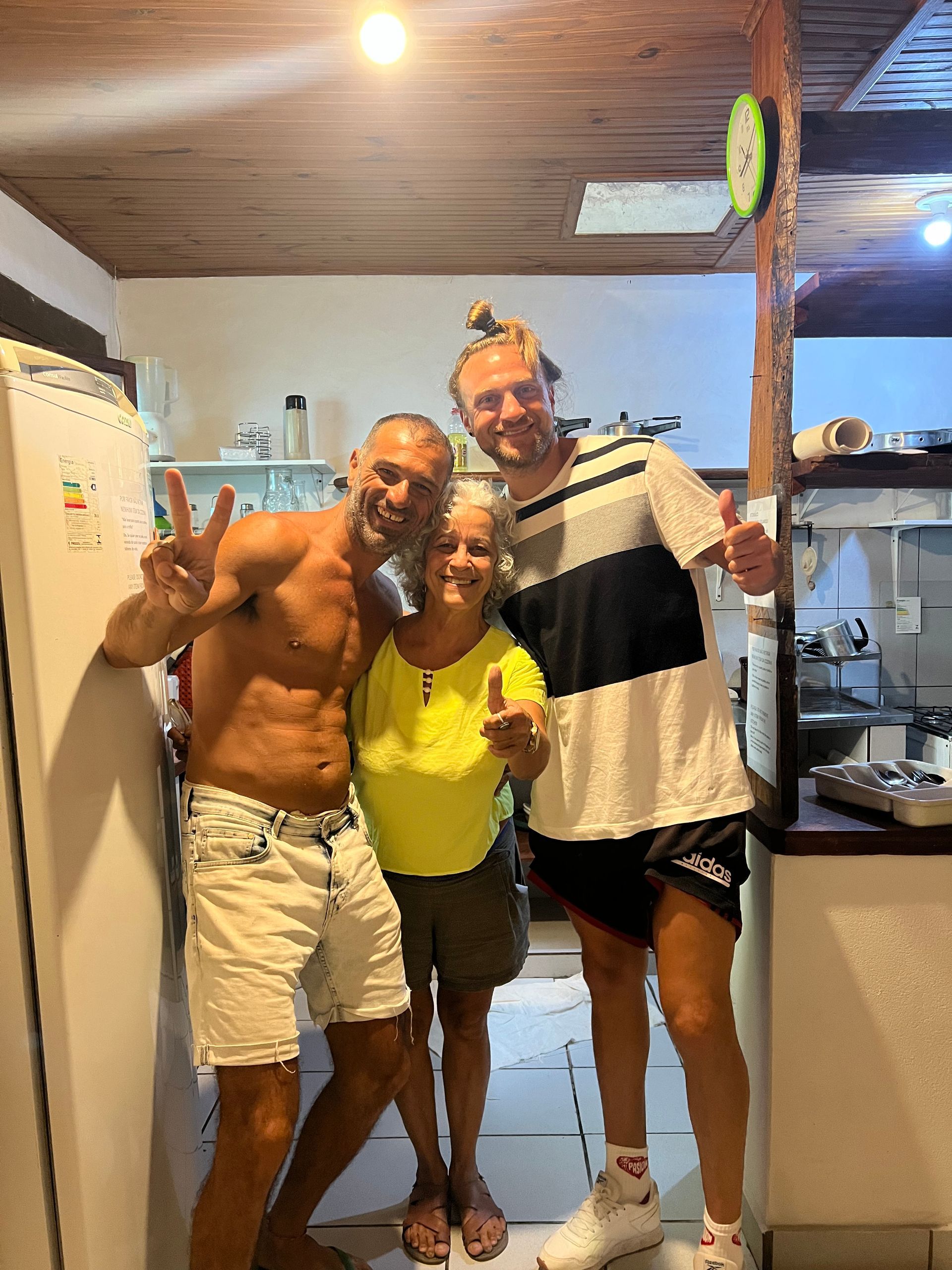 Três homens e uma mulher estão posando para uma foto em uma cozinha.