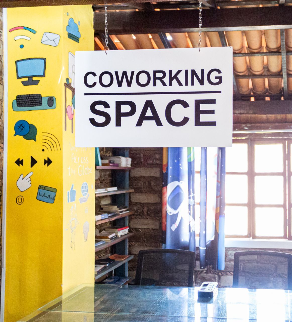 Uma sala com uma mesa e cadeiras e uma placa que diz espaço de coworking