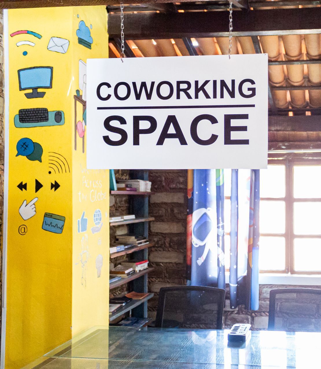 Uma sala com uma mesa e cadeiras e uma placa que diz espaço de coworking