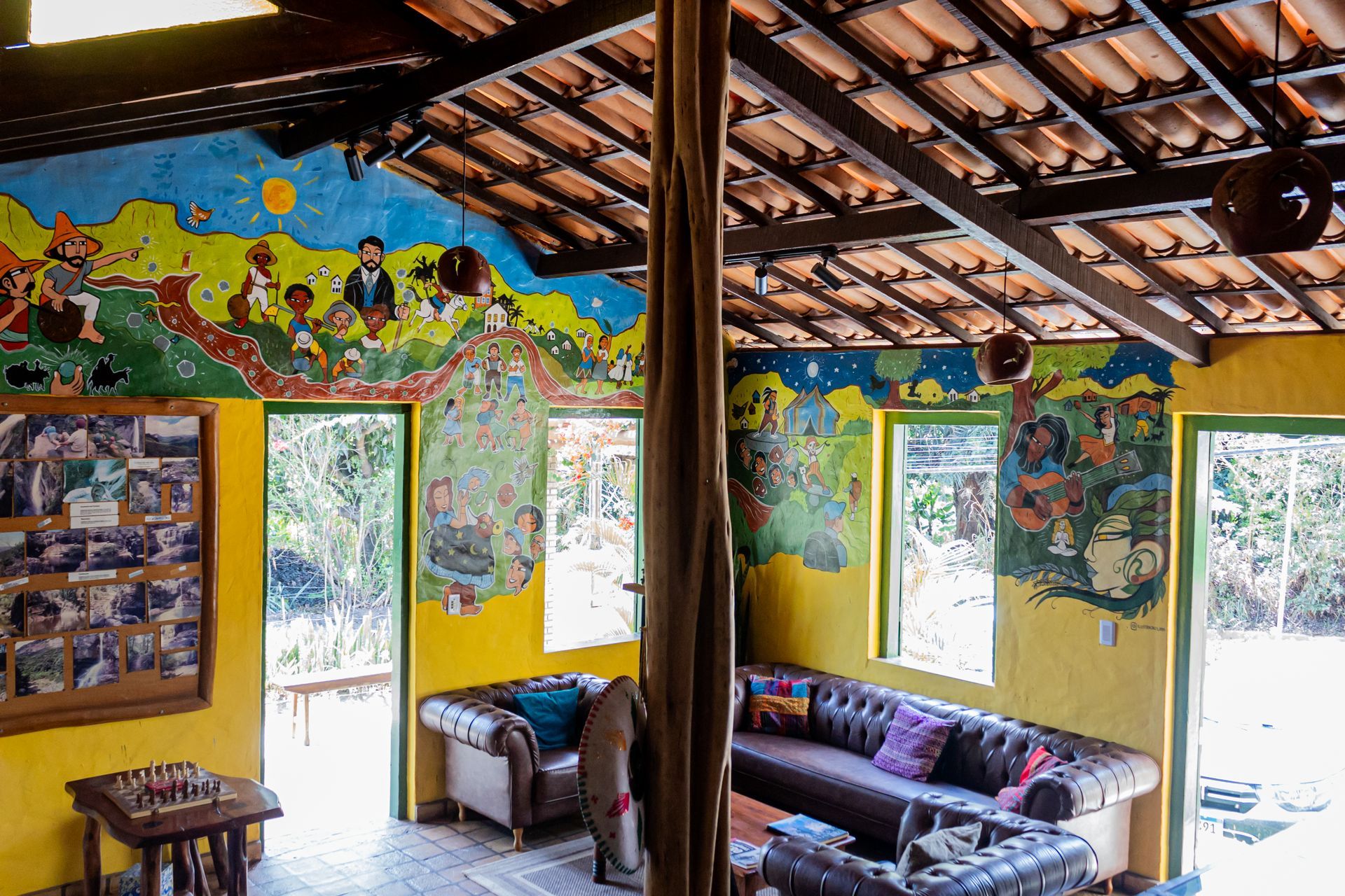 Uma sala de estar em uma cabana de madeira com um sofá, cadeira, mesa e televisão.