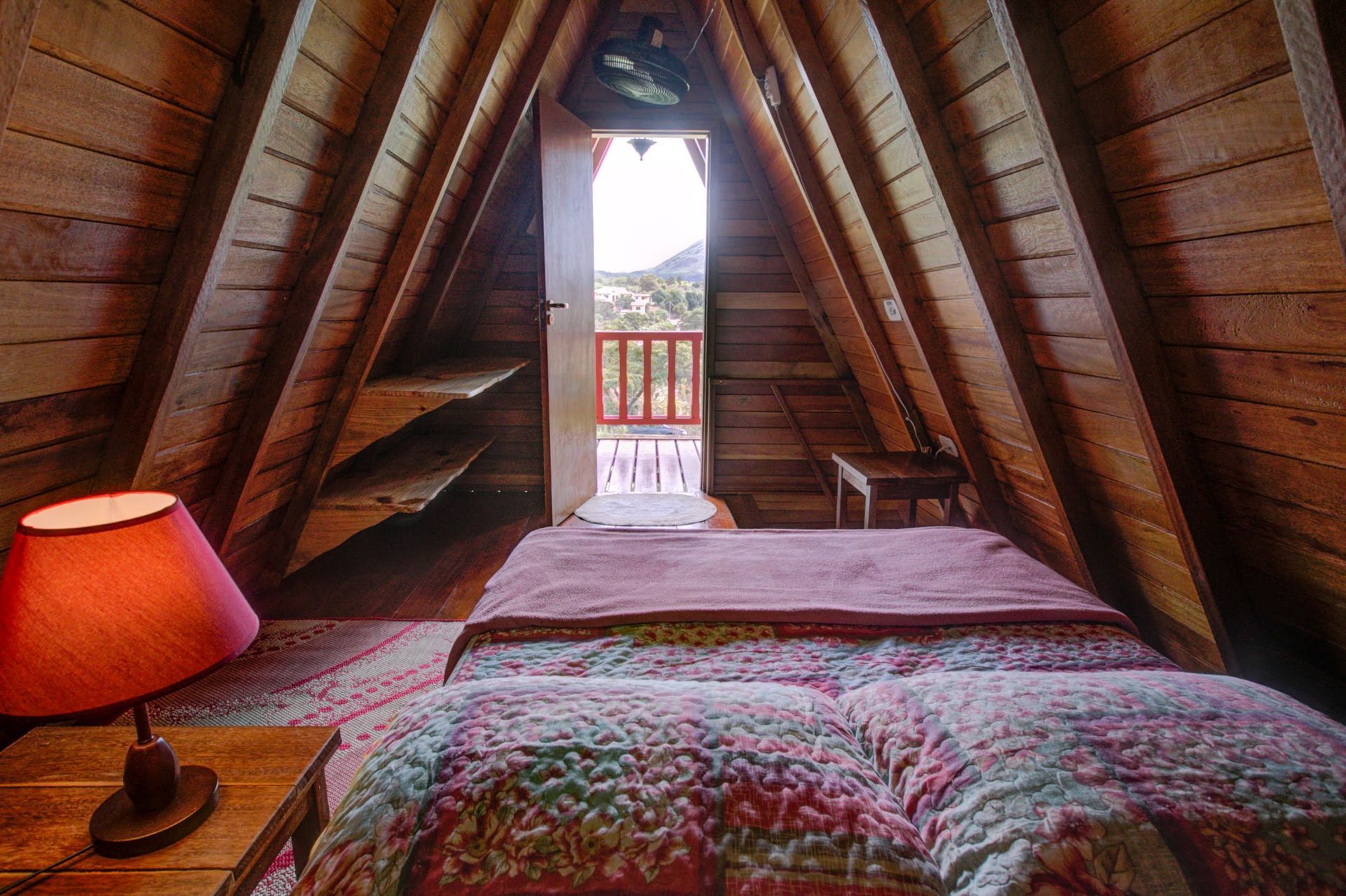 Há uma cama no sótão de uma casa de madeira.