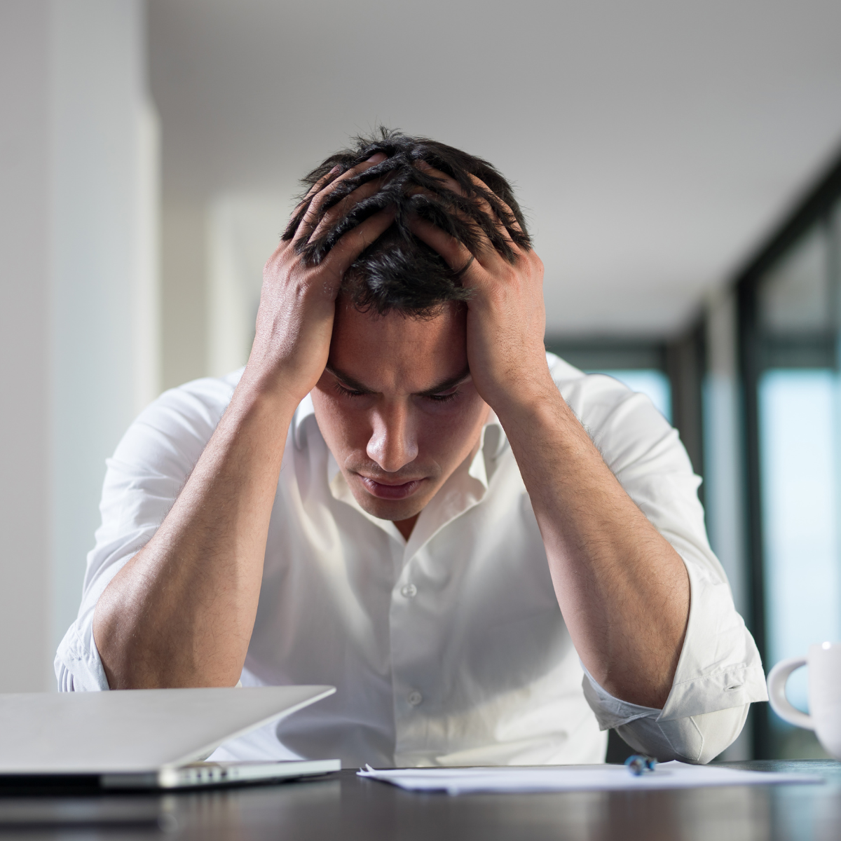 A man sitting at a desk with his hands on his head