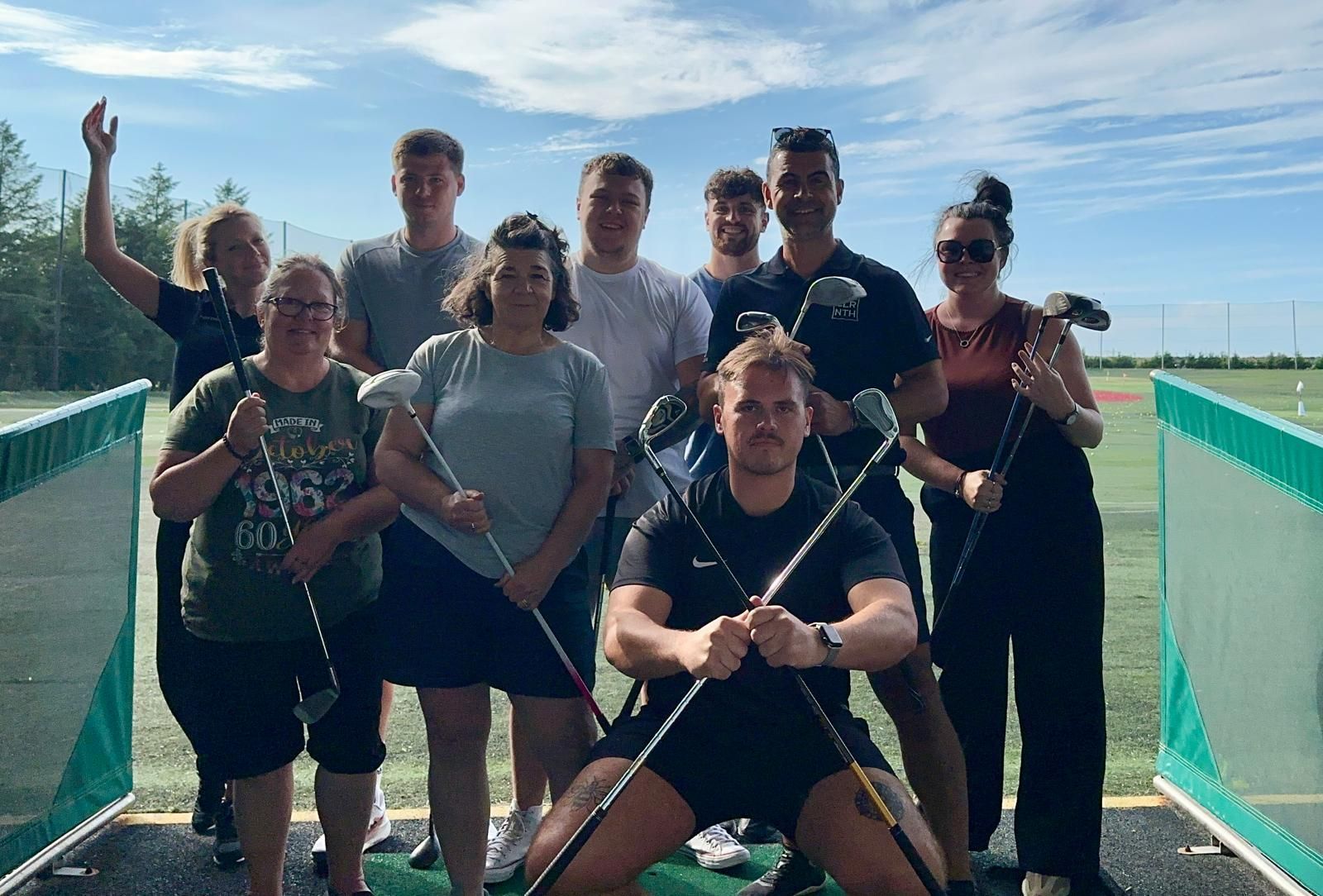 A group of people are posing for a picture while holding golf clubs.
