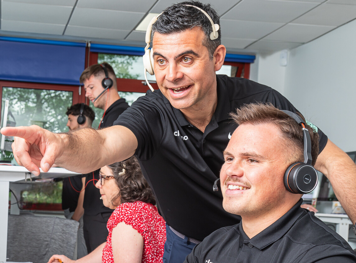 A man is pointing at another man while wearing headphones.